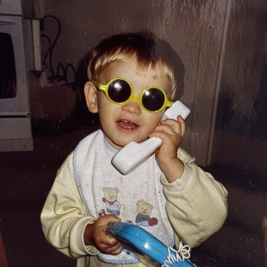 Liam als Kind mit Spielzeugtelefon und Sonnenbrille